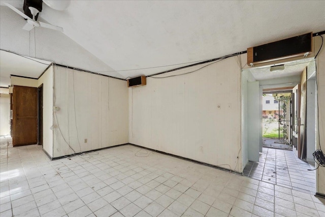 spare room with wooden walls, a ceiling fan, and vaulted ceiling