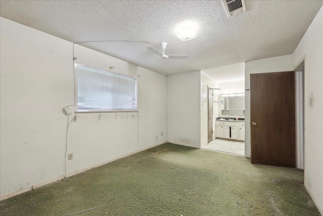 carpeted spare room featuring visible vents, a ceiling fan, and a textured ceiling