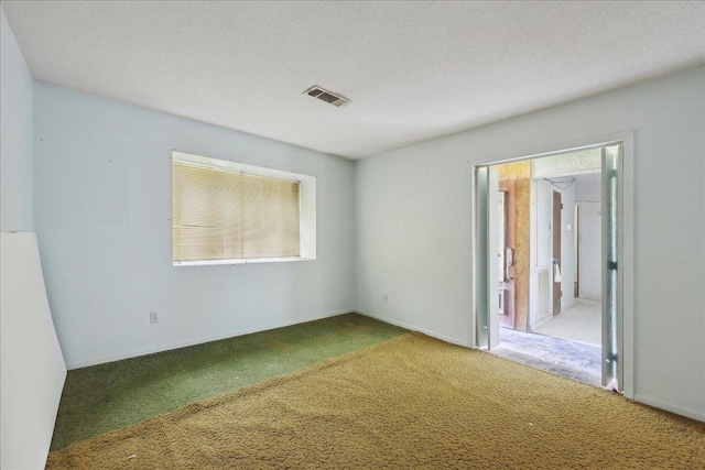 unfurnished bedroom with a textured ceiling, visible vents, and carpet