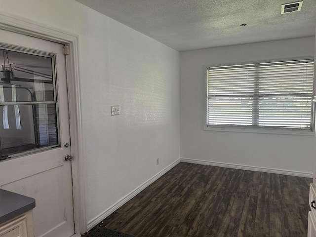 unfurnished room with a healthy amount of sunlight, dark hardwood / wood-style flooring, and a textured ceiling