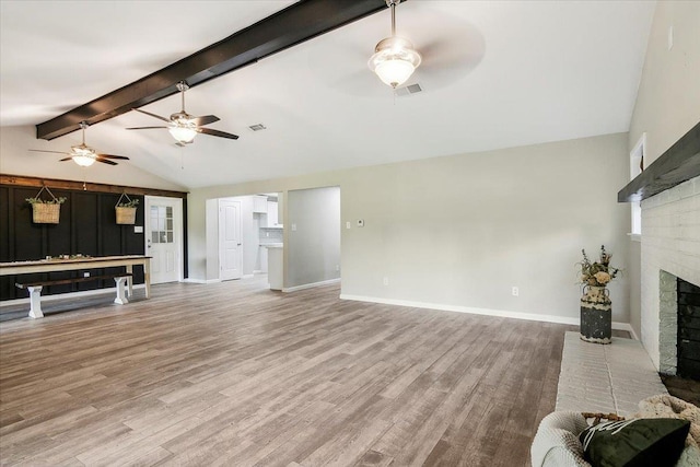 living room featuring hardwood / wood-style flooring, lofted ceiling with beams, and a brick fireplace