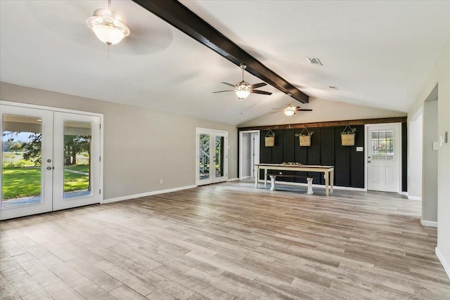 unfurnished living room featuring french doors, lofted ceiling with beams, plenty of natural light, and light hardwood / wood-style flooring