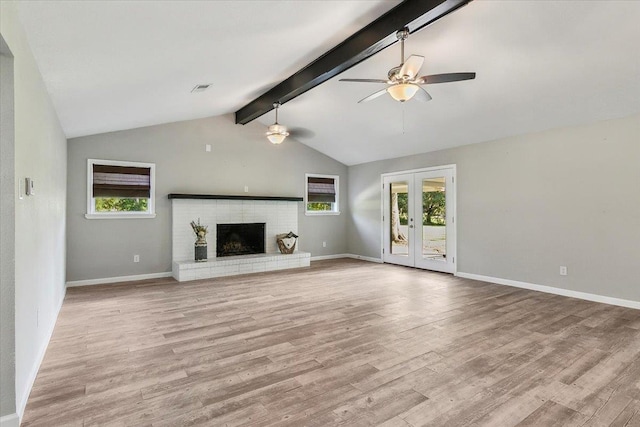 unfurnished living room with french doors, light wood-type flooring, a brick fireplace, ceiling fan, and vaulted ceiling with beams