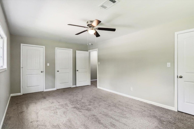 unfurnished bedroom with ceiling fan, carpet, and two closets