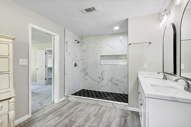 bathroom with vanity, a tile shower, and wood-type flooring