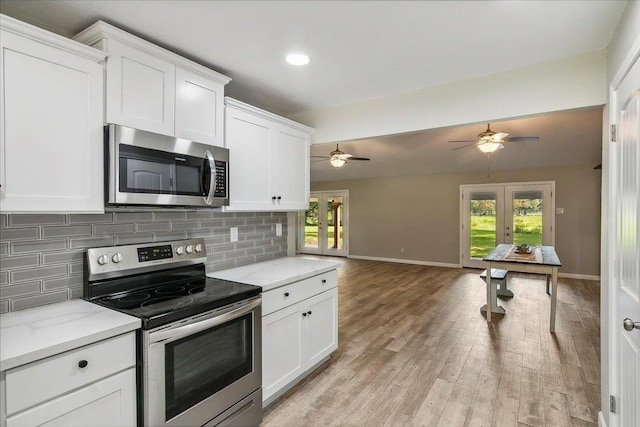 kitchen with french doors, backsplash, light stone counters, stainless steel appliances, and white cabinets