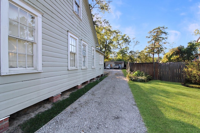 view of side of home with fence and a yard