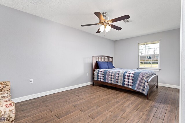314 Pinehurst Dr, Sour Lake, TX 77659 - bedroom with visible vents, a ceiling fan, a textured ceiling, wood finished floors, and baseboards