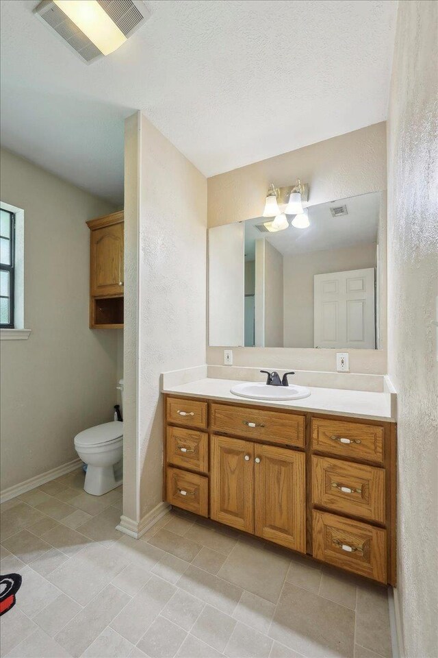 504 County Road 763 N, Buna, TX 77612 - bathroom with toilet, vanity, a textured wall, baseboards, and tile patterned floors
