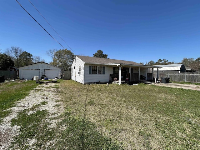 back of house with a detached garage, fence, a lawn, and an outbuilding