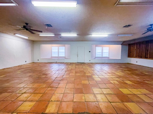 empty room featuring light tile patterned floors, a textured ceiling, and ceiling fan