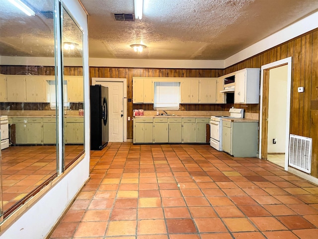 kitchen with stove, black refrigerator with ice dispenser, a textured ceiling, sink, and white stove