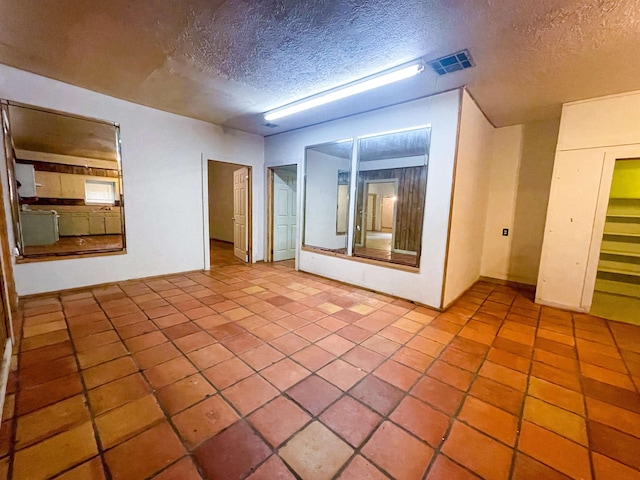 tiled empty room featuring a textured ceiling