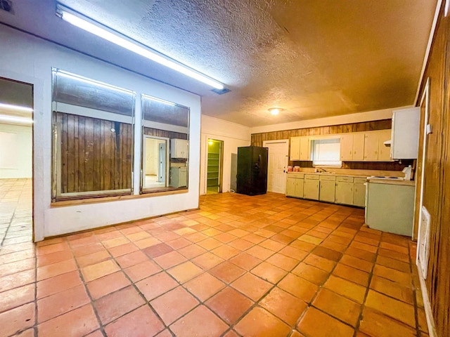 kitchen featuring a textured ceiling and black fridge