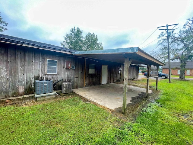 rear view of property featuring a yard, cooling unit, and a carport