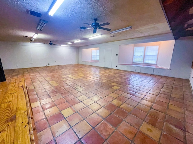 unfurnished room featuring ceiling fan, plenty of natural light, and a textured ceiling