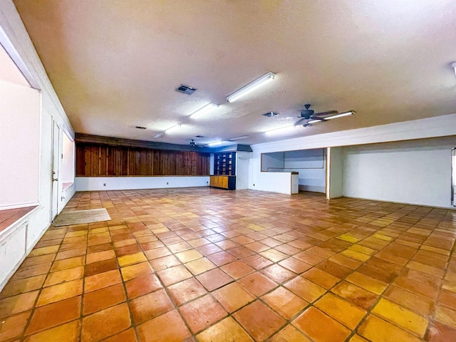 interior space with a textured ceiling, ceiling fan, and light tile patterned flooring