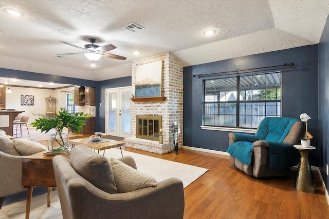 living room with lofted ceiling, french doors, ceiling fan, a textured ceiling, and wood-type flooring