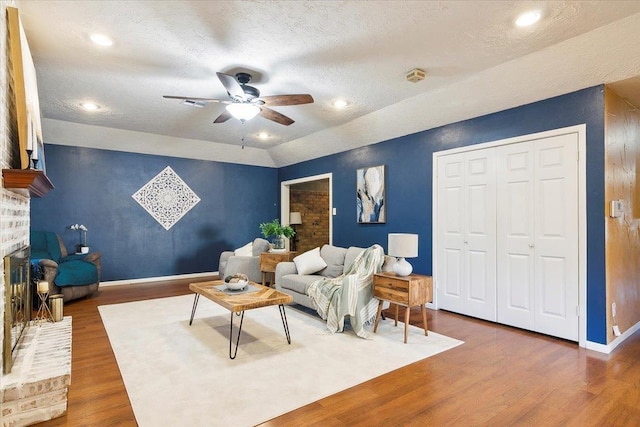 living room with a textured ceiling, ceiling fan, dark hardwood / wood-style flooring, and lofted ceiling