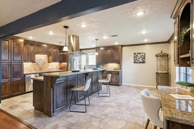 kitchen featuring tasteful backsplash, decorative light fixtures, island range hood, a center island with sink, and appliances with stainless steel finishes