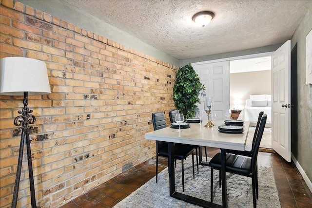 dining space with brick wall and a textured ceiling