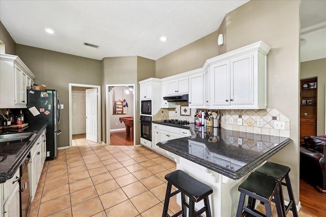 1416 23rd St, Nederland, TX 77627 - kitchen featuring white cabinets, a peninsula, backsplash, a kitchen bar, and recessed lighting