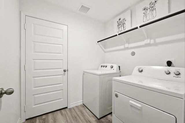 clothes washing area featuring washer and dryer, laundry area, light wood-style floors, and visible vents