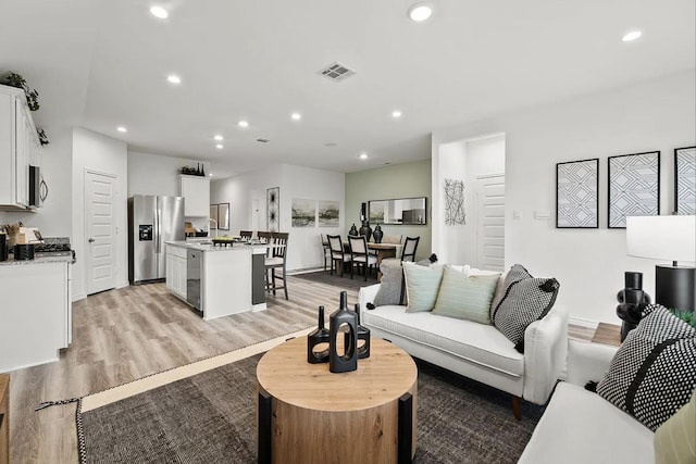 living area with visible vents, recessed lighting, and light wood-type flooring