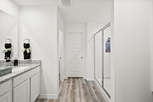 bathroom with visible vents, wood finished floors, a shower stall, baseboards, and vanity