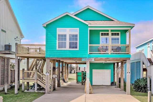 raised beach house with a garage, a carport, and covered porch