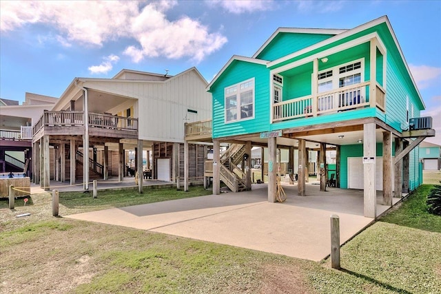 back of property featuring a carport, a balcony, cooling unit, and a lawn