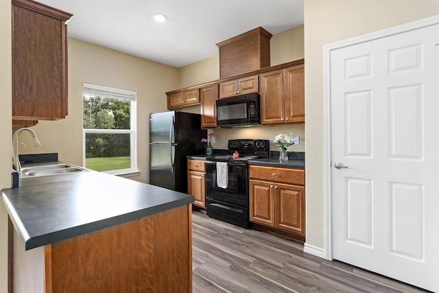 451 Lene Ln, Beaumont, TX 77705 - kitchen featuring black appliances, dark countertops, wood finished floors, brown cabinetry, and recessed lighting