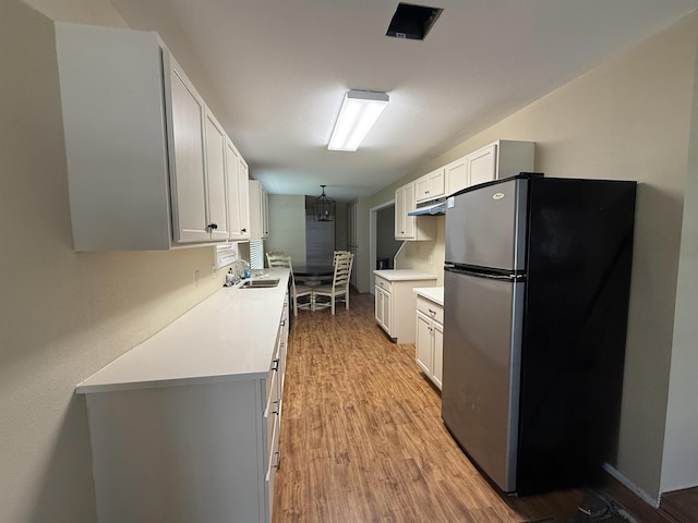 445 Longmeadow, Beaumont, TX 77707 - kitchen featuring freestanding refrigerator, light wood finished floors, light countertops, white cabinets, and under cabinet range hood