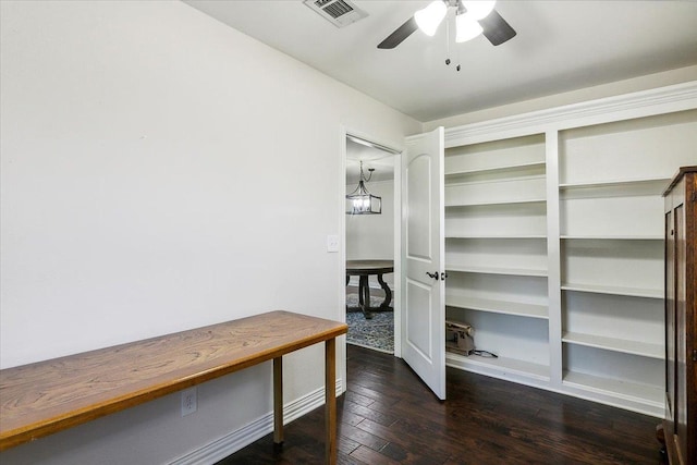 spacious closet with ceiling fan with notable chandelier and dark hardwood / wood-style flooring