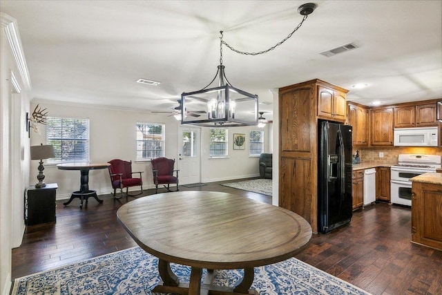 kitchen with decorative backsplash, ceiling fan with notable chandelier, white appliances, dark wood-type flooring, and hanging light fixtures