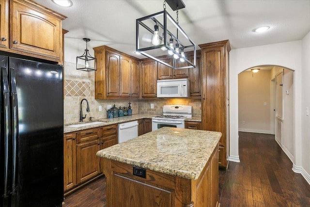 kitchen featuring white appliances, sink, hanging light fixtures, a kitchen island, and dark hardwood / wood-style flooring