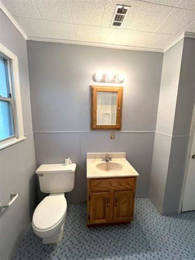 bathroom featuring toilet, visible vents, crown molding, and vanity