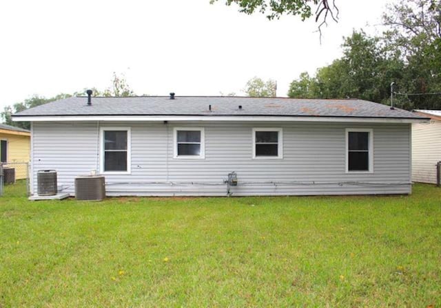 back of house featuring a yard, central AC unit, and fence