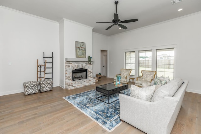 living room with ornamental molding, a brick fireplace, hardwood / wood-style floors, and ceiling fan