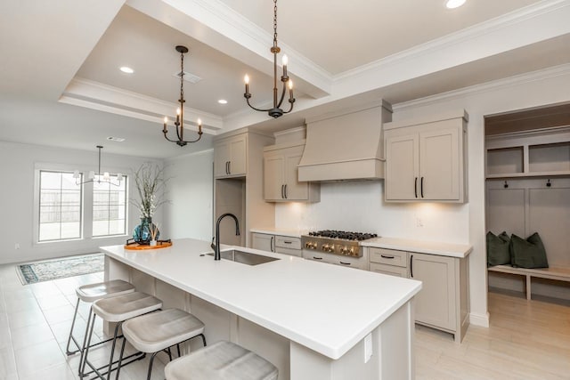 kitchen featuring premium range hood, a large island, sink, and a tray ceiling