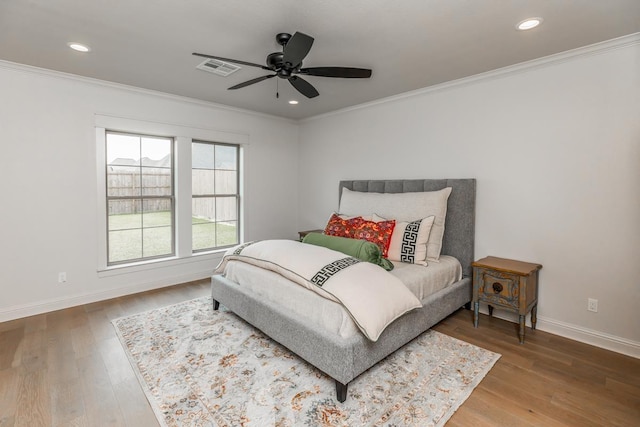 bedroom with hardwood / wood-style flooring, ceiling fan, and ornamental molding