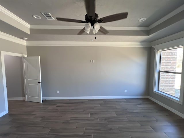 unfurnished room featuring dark wood-style flooring, a raised ceiling, visible vents, and crown molding