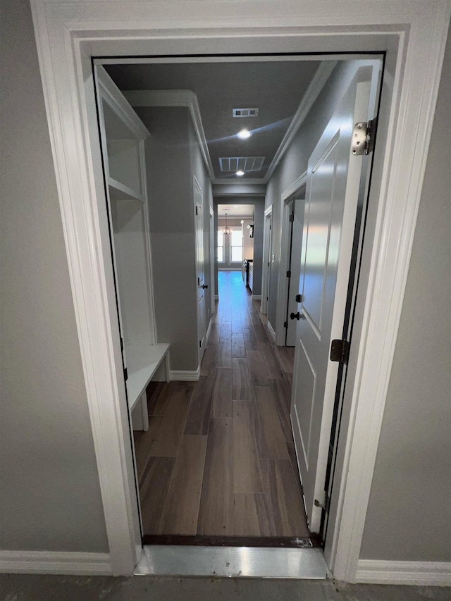 hallway featuring ornamental molding, dark wood finished floors, visible vents, and baseboards