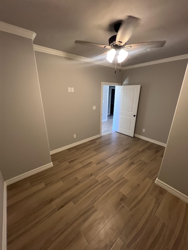 spare room featuring a ceiling fan, baseboards, dark wood-style flooring, and crown molding