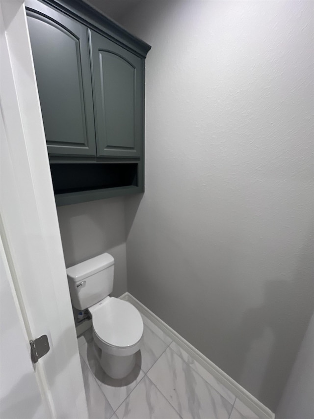 bathroom featuring marble finish floor, toilet, and baseboards