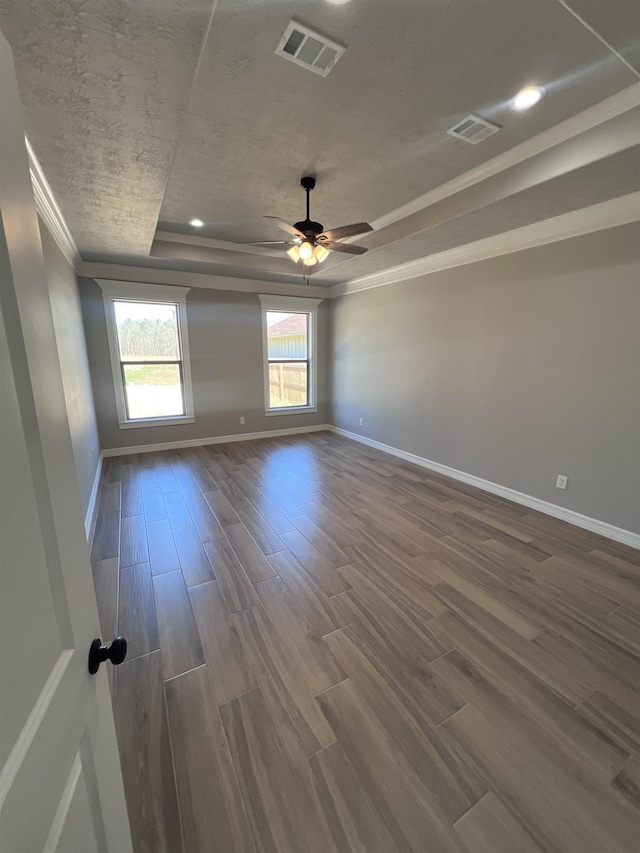 empty room with baseboards, visible vents, a raised ceiling, and dark wood finished floors