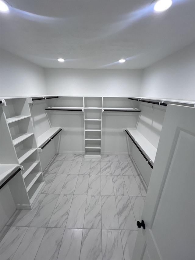 walk in closet featuring marble finish floor