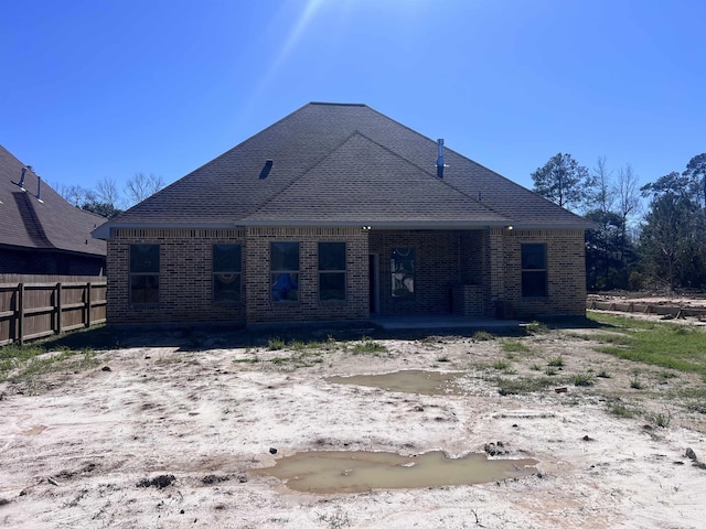 rear view of property featuring fence, a patio, and brick siding