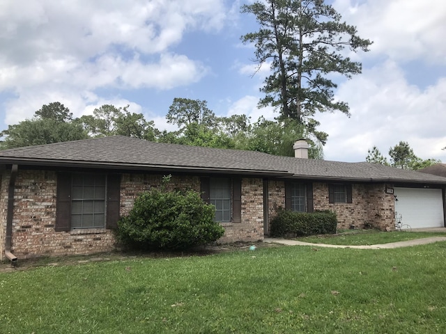ranch-style house featuring a chimney, roof with shingles, a front yard, a garage, and brick siding