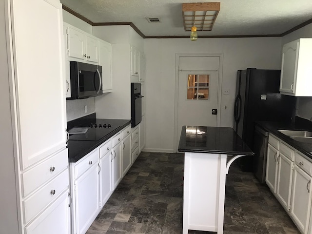 kitchen with white cabinetry, dark countertops, visible vents, and black appliances
